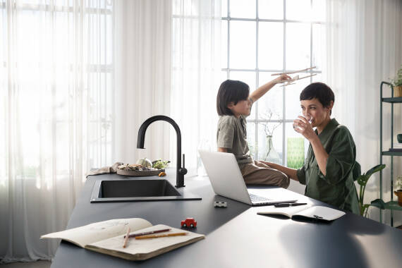 Woman with son at the kitchen island with the hansgrohe Aqittura M91.