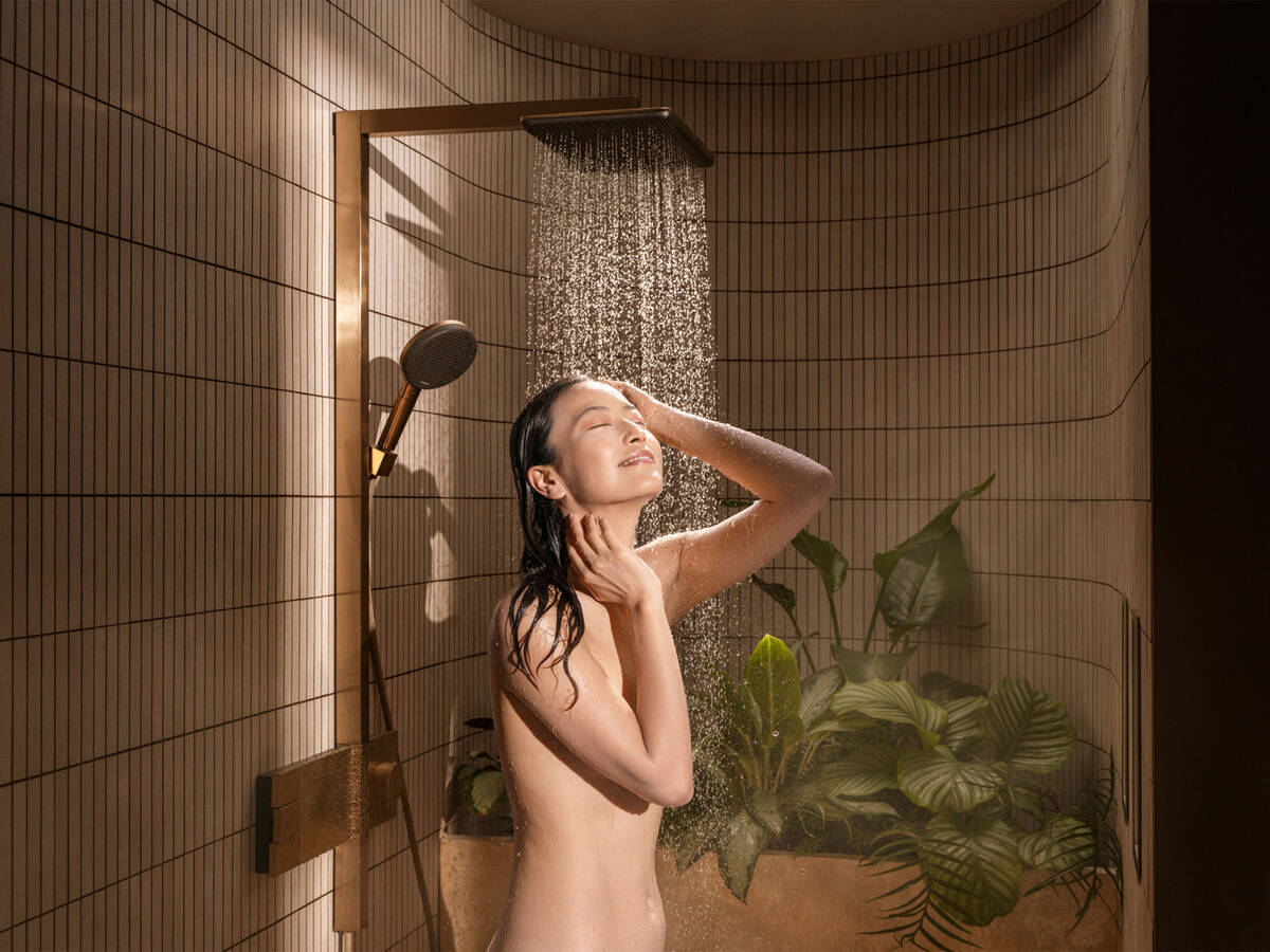 女士站在雨淋式淋浴下。