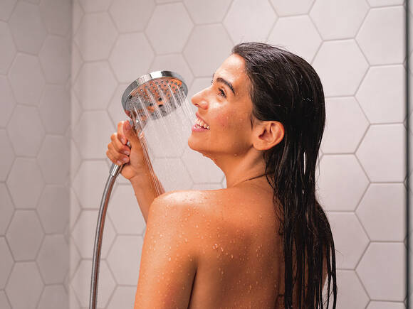 Woman showering with Raindance Select S hand shower.