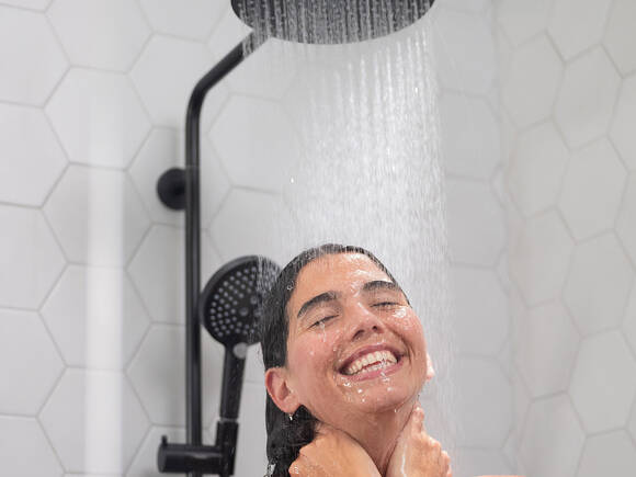 Woman enjoying the Raindance Select S shower pipe.