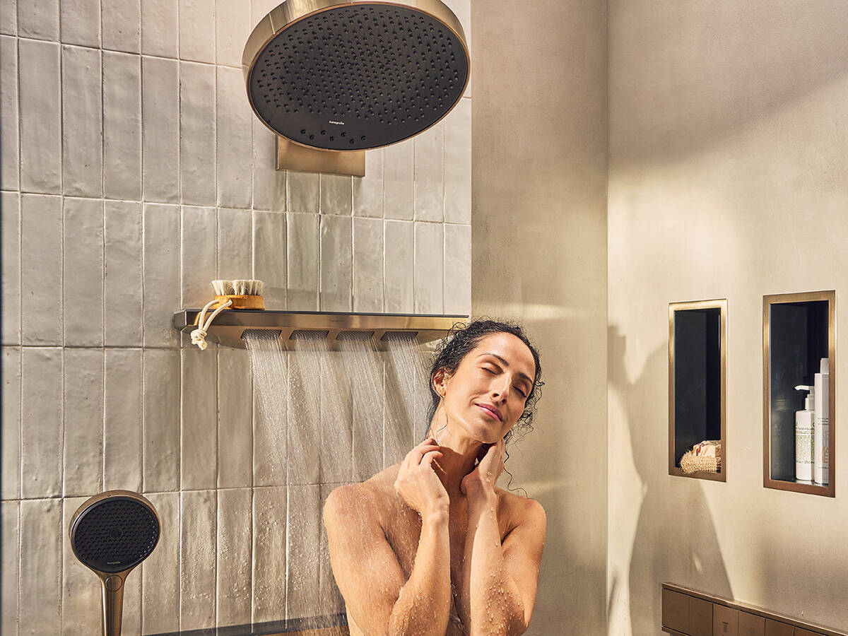 女士在奢华浴室的境雨肩部花洒下享受淋浴。