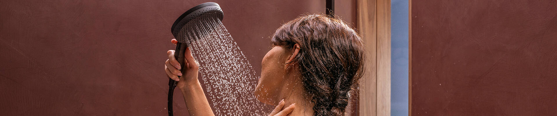 一位女士正在使用汉斯格雅飞雨 Alive 手持花洒淋浴。