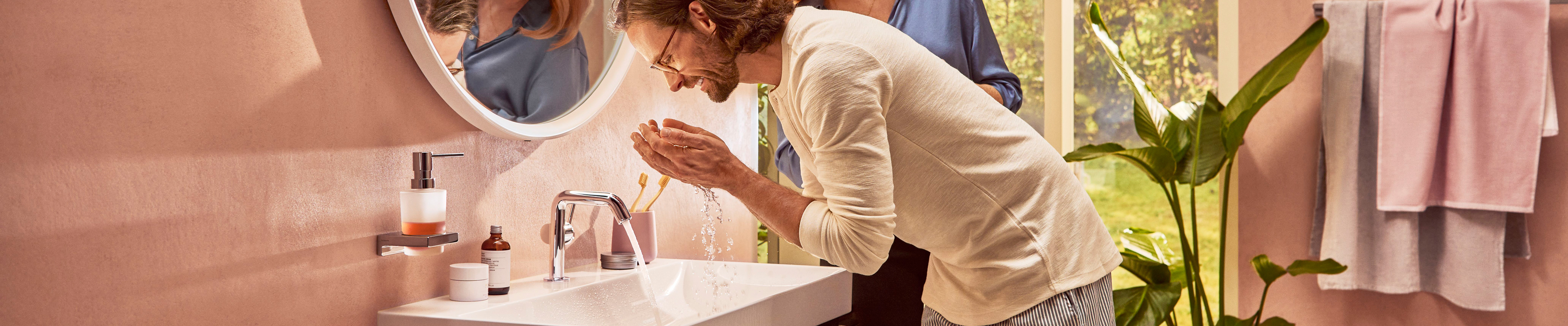 男士在配有 Tecturis S 台盆龙头的汉斯格雅台盆处。