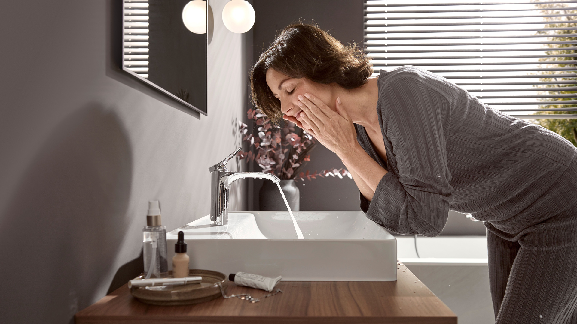 女士在台盆和 Vivenis薇怡斯 浴室龙头旁。