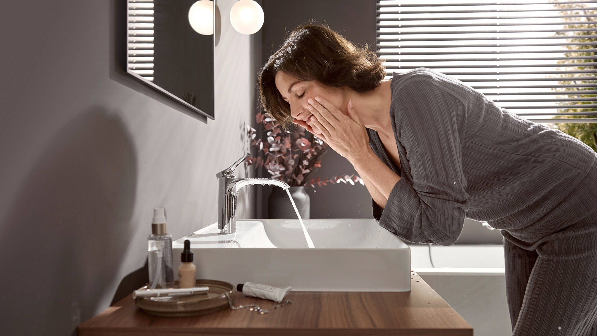 女士在台盆和 Vivenis薇怡斯 浴室龙头旁。